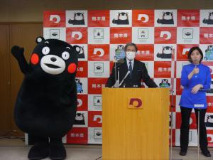 コメントする蒲島知事とくまモン利用商品売上高の更新を喜ぶくまモンの写真