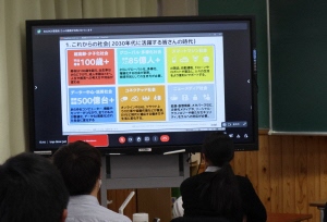 オンライン講演会で電子黒板に映し出されている資料を生徒が見ている様子の写真