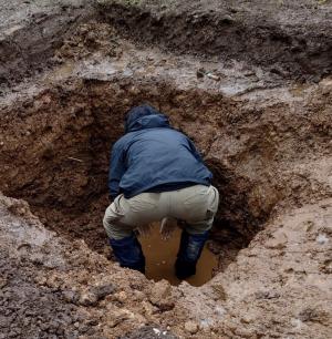 土壌に深さ1m程度の穴を掘り、排水不良の原因を探る様子