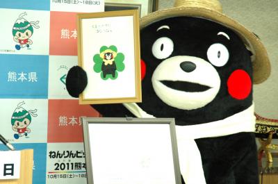 くまもとグリーン農業シンボルマークを持つくまモンの写真