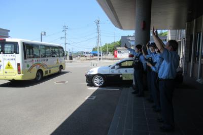 幼稚園のバスを手を振って見送る警察官たち